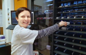 Zu sehen ist eine Mitarbeiterin beim Einlagern am Kommssionierautomaten