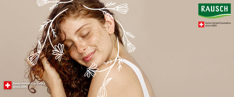 Junge langhaarige Frau genießt es Ihr gepflegtes Harr zu berühren und verschließt dabei die Augen